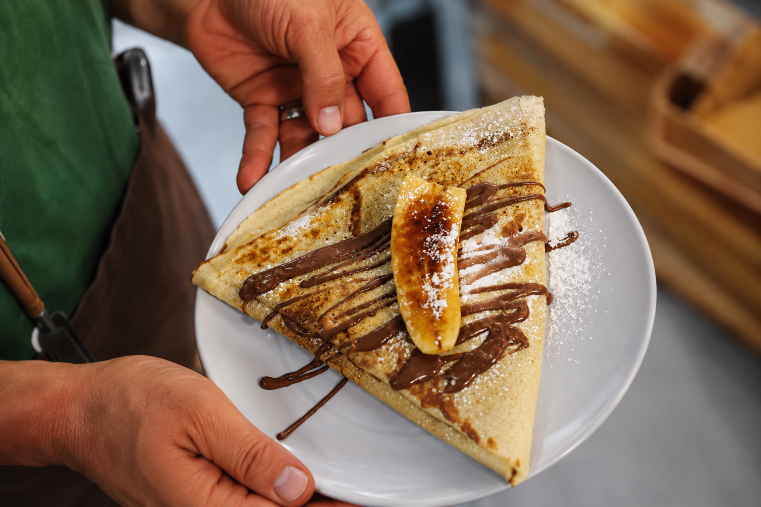 A banana and chocolate cr&ecirc;pe handed over on a white plate